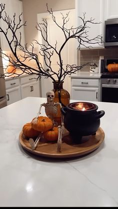 a white kitchen counter top topped with a bowl filled with pumpkins and skeleton figurines