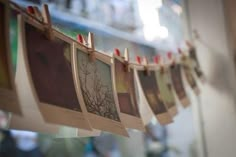 several pictures hanging on clothes pins in front of a wall