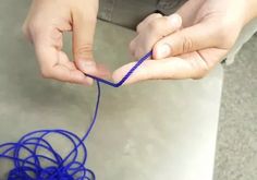 two hands are holding blue string on the floor