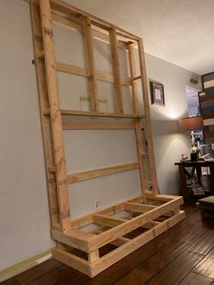 an unfinished bed frame sitting on top of a hard wood floor in a living room