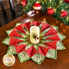 a candle is sitting on top of a table with red and green napkins in front of a christmas tree