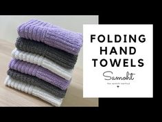 four folded towels sitting on top of a wooden table next to a white and black sign that says folding hand towels