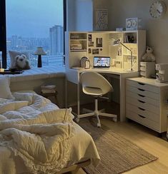 a bedroom with a bed, desk and window overlooking the cityscape at night