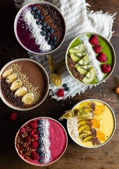 three bowls filled with different types of smoothie and fruit on top of a table