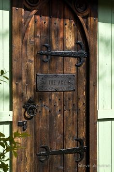 an old wooden door with iron handles and a sign that says the ark on it