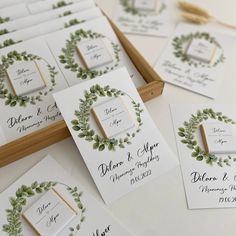 the wedding stationery is laid out on top of each other, with greenery