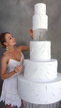 a woman is leaning on a large white cake