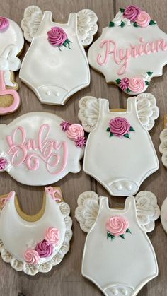 baby shower cookies decorated with pink and white icing on a wooden table, ready to be eaten