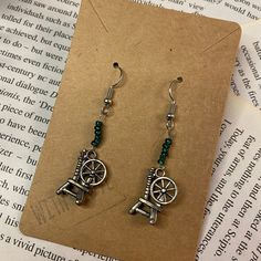 Earring themed for twisted wonderland's dark and malevolent dorm of Diasomnia. Simple emerald and spinning wheel charmed earrings. Diasomnia Dorm, Maleficent Sleeping Beauty, Spinning Wheel, Twisted Wonderland, Maleficent, Charm Earrings, Gibson, Spinning, Jewelry Earrings Dangle