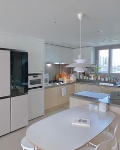 a kitchen with white cabinets and an island table in the middle, along with a large window