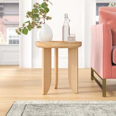 a living room with a pink chair, table and vase on the floor next to it