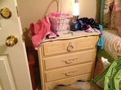 a white dresser sitting in a bedroom next to a bed with pink and green bedspread