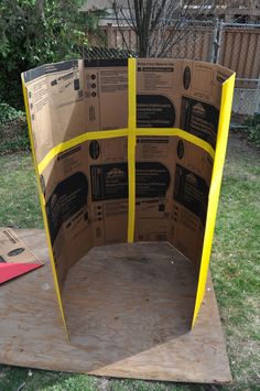 an open cardboard box sitting on top of a piece of wood in the middle of a yard