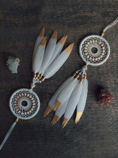 two white and gold dream catchers sitting on top of a wooden table