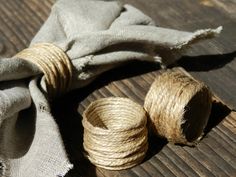 two twine spools on top of a wooden table next to a piece of cloth