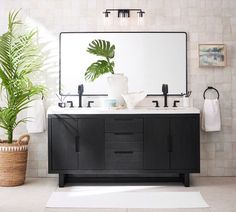 a bathroom vanity with two sinks and a large plant in the corner next to it