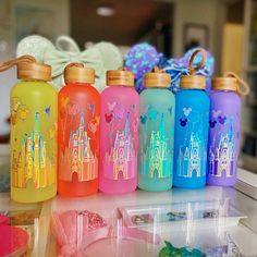 several water bottles with disney castle designs on them