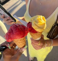 two scoops of ice cream are being held up by women's hands in yellow dresses