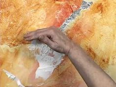 a person is cutting paper with scissors on a piece of art that has been painted yellow and orange