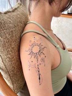 a woman with a sun tattoo on her arm and shoulder, sitting in a chair