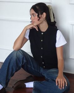 a woman sitting on the floor with her hand under her chin