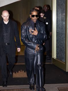 two men in black leather outfits walking down the street