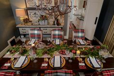 the table is set for christmas dinner with plaid napkins and place settings on it