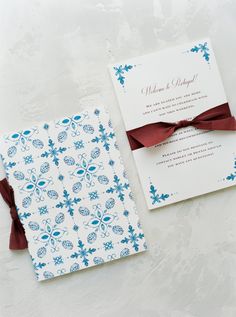 the wedding stationery is decorated with blue and white flowers, red ribbon, and a matching pocketfold