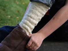 a person sitting on the ground with their foot in a pair of brown boots and socks