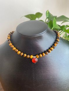 This choker is from my beauty of the Southwest Collection. A beautiful vibrant red-orange carnelian centerpiece is surrounded by tigers' eye gemstones. The necklace length is 16." Carnelian pendant is 10mm round, tiger's eye beads are 6mm each. Completely finished in sterling silver. Gift box included. Enjoy complimentary domestic shipping. The necklace will ship within 3-5 business days. Thank you, Althea Morgan-Campbell Brown Gemstone Beaded Necklace, Spiritual Brown Choker As Gift, Spiritual Brown Choker Gift, Carnelian Jewelry For Meditation In Brown, Brown Carnelian Jewelry For Meditation, Wooden Bead Jewelry, Silver Gift Box, Carnelian Pendant, My Beauty