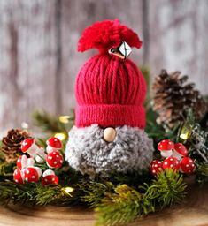 a knitted santa clause hat sitting on top of a wooden table next to pine cones