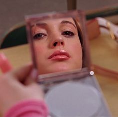 a woman looking at her face in the mirror