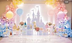 a table topped with lots of balloons next to a castle and castle cake on top of a table