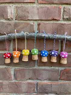 small colorful mushrooms are hanging from a branch on a brick wall in front of a brick wall