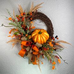 a wreath decorated with orange and brown fall flowers is hanging on the wall next to a door