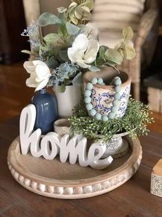 there is a vase with flowers in it on the table next to a sign that says home