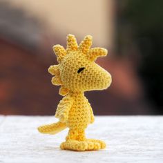 a small yellow crocheted giraffe standing on top of a white surface