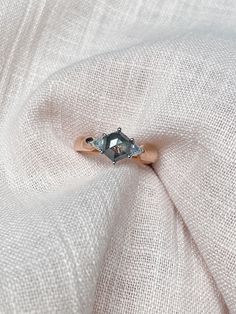 an engagement ring on top of a white cloth with a diamond in the center,