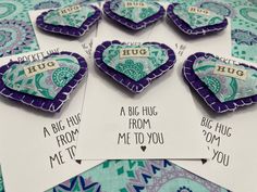 six purple and green heart shaped magnets sitting on top of a blue patterned table cloth