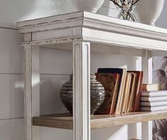 a book shelf with books on top of it and vases in the back ground