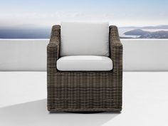 a wicker chair sitting on top of a white floor next to an ocean view