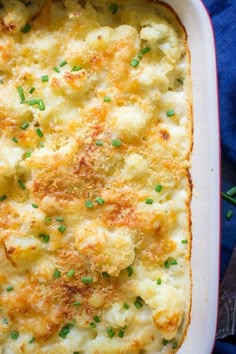 a casserole dish with cheese and scallions in it on a blue cloth