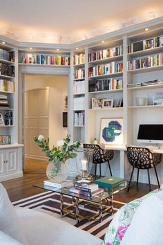 a living room filled with lots of furniture and bookshelves full of books on top of them