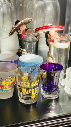 several shot glasses are lined up on a table with figurines in the background