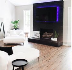 a living room with white furniture and a flat screen tv mounted on the wall above a fireplace