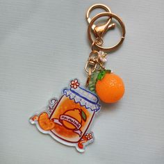 an orange is sitting on top of a keychain that has a jar of marmalade in it