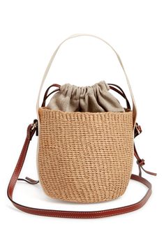 Elevate your warm-weather look with this compact basket bag handwoven by independent craftswomen in Kenya from partially upcycled materials. A drawstring lining keeps items secured, while a leather strap and logo-embellished Woody strap offer carrying options. Drawstring closure Top carry handle; adjustable shoulder strap Paper with textile and leather trim Due to the handmade nature, each item is one of a kind Made in Kenya Designer Handbags This product is Fair Trade Certified™ and was made us Everyday Woven Leather Bucket Bag, Chic Bucket Straw Bag With Removable Pouch, Chic Straw Bucket Bag With Removable Pouch, Beige Woven Leather Bucket Bag, Everyday Use Bucket Bag In Woven Leather, Eco-friendly Top Handle Bucket Bag With Leather Handles, Eco-friendly Bucket Bag With Leather Handles, Beach Bucket Bag With Top Handle And Removable Pouch, Beach Bucket Bag With Removable Pouch And Top Handle