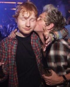 two men kissing each other at a party