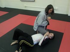 two people in a gym with one laying on the ground and another standing over him