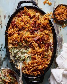 a casserole dish with bacon, green beans and onions in it on a blue table